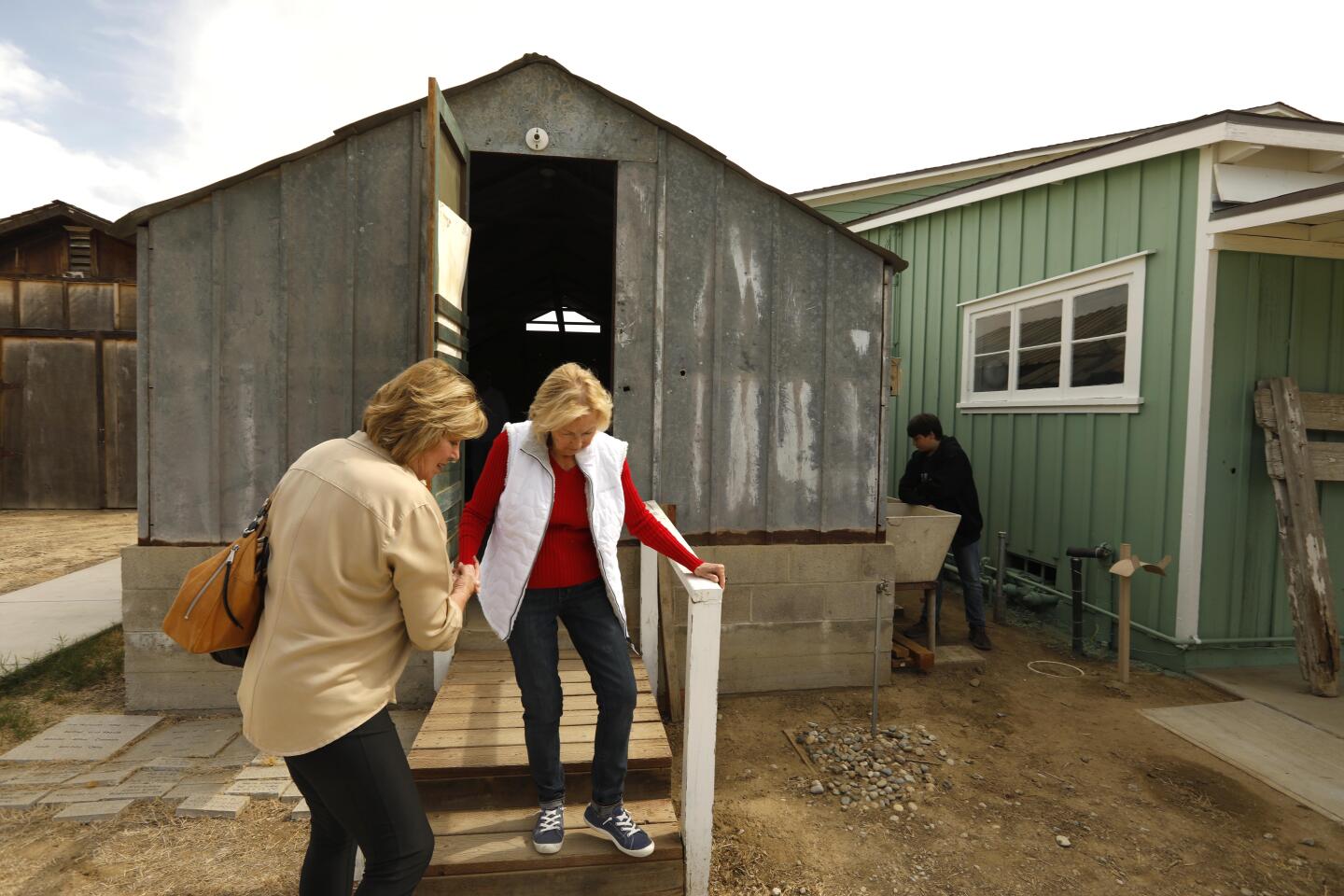 BAKERSFIELD, CA - OCTOBER 19, 2019 - - Pat Rush, 84, with the help of her daughter Angie Trigueiro, , exits one of the structures she and her family used to live in after migrating from Oklahoma to Bakersfield in 1945. Rush was revisiting the Weedpatch Camp with her daughter in Bakersfield on October 19, 2019. After three decades, the Dust Bowl Days festival at Weedpatch Camp, which housed Okies and migrant workers during the Dust Bowl, is ending its run. The final festival celebrates Okie history. (Genaro Molina / Los Angeles Times)