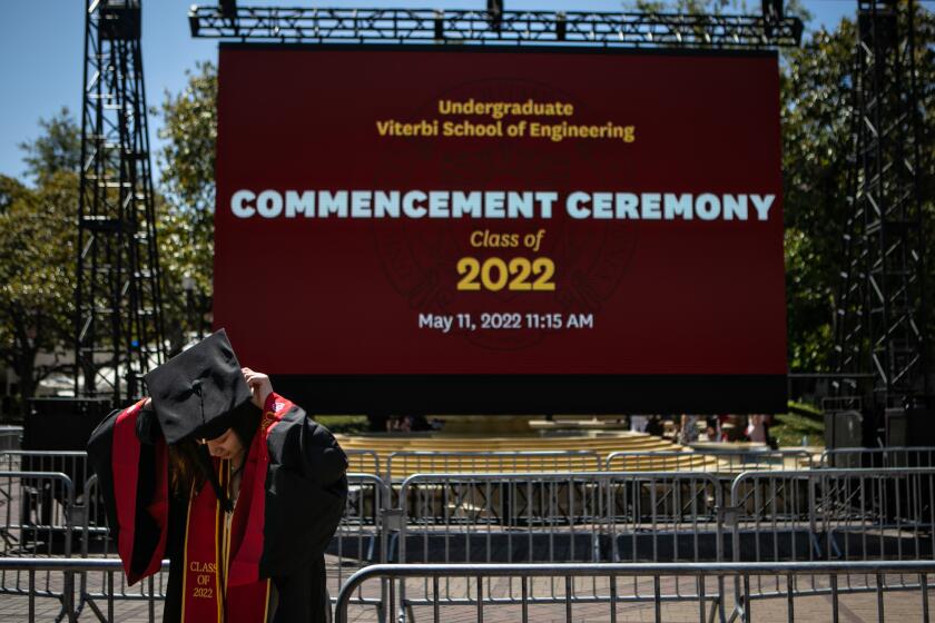 LOS ANGELES, CA - MAY 13: A graduate puts on her cap before posing for a photo at USC's commencement ceremony on Friday, May 13, 2022 in Los Angeles, CA. (Jason Armond / Los Angeles Times)