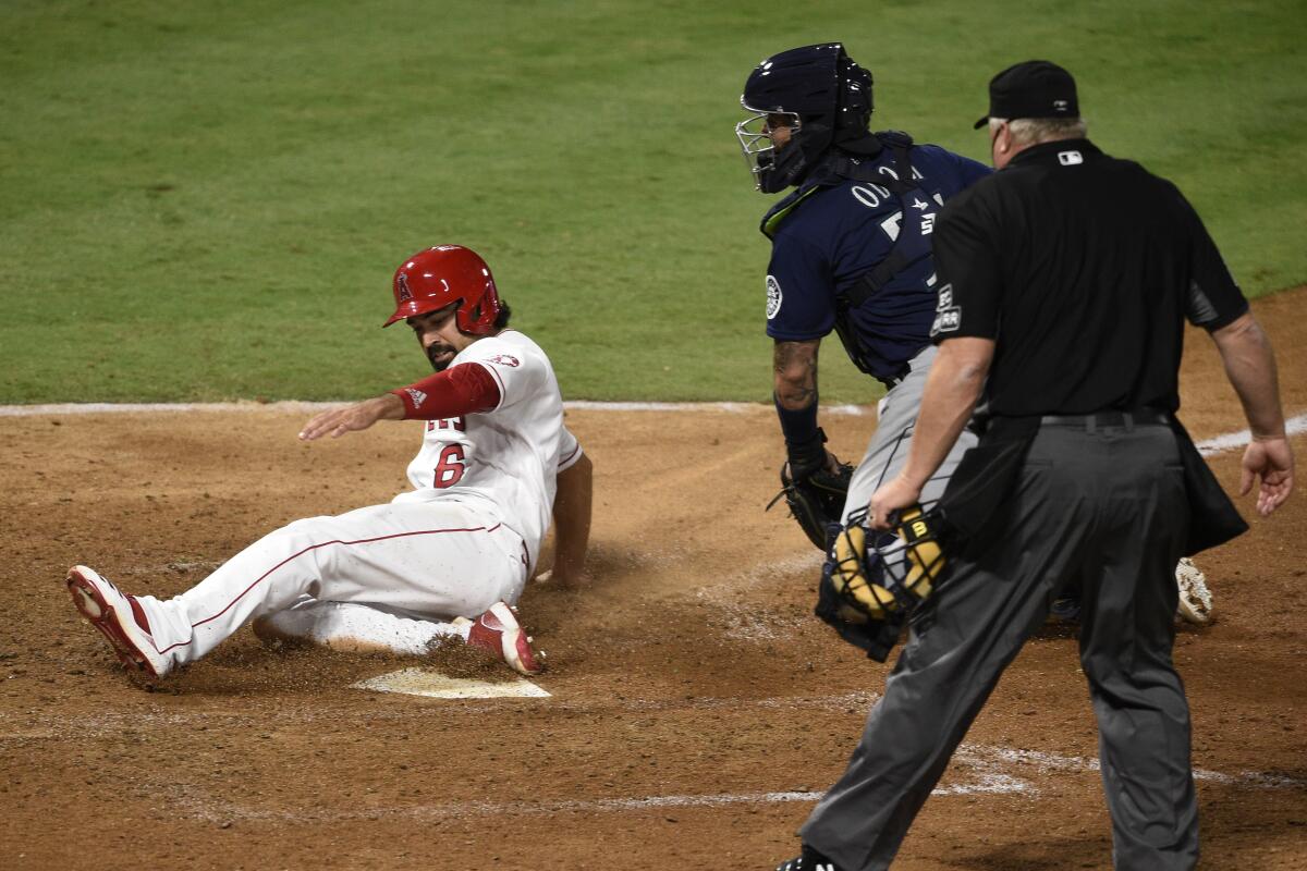 Angels third baseman Anthony Rendon, left, slides into home past Seattle Mariners catcher Joseph Odom.