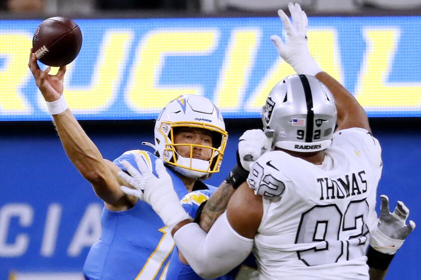 Inglewood CA, Monday, October 4, 2021 - Los Angeles Chargers quarterback Justin Herbert (10) attempts a pass under pressure from Las Vegas Raiders defensive end Solomon Thomas (92) at SoFi Stadium. (Robert Gauthier/Los Angeles Times)