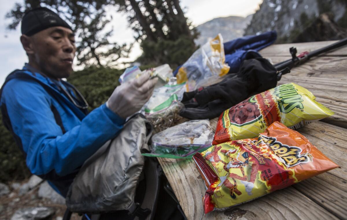 Sam Kim takes a break with spicy Cheetos and Funyuns, favorite foods to power him along, at the San Antonio Ski Hut at 8,300 feet along the trail to Mt. Baldy.