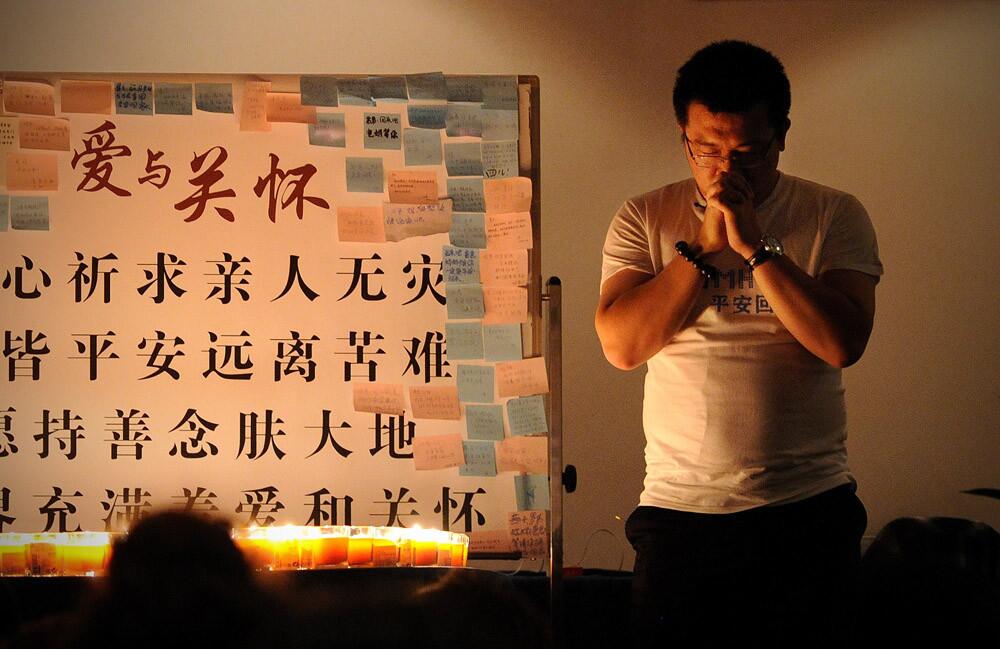 A Chinese relative of passengers from missing Malaysia Airlines flight MH370 prays before a meeting at the Metro Park Lido Hotel in Beijing on March 31.