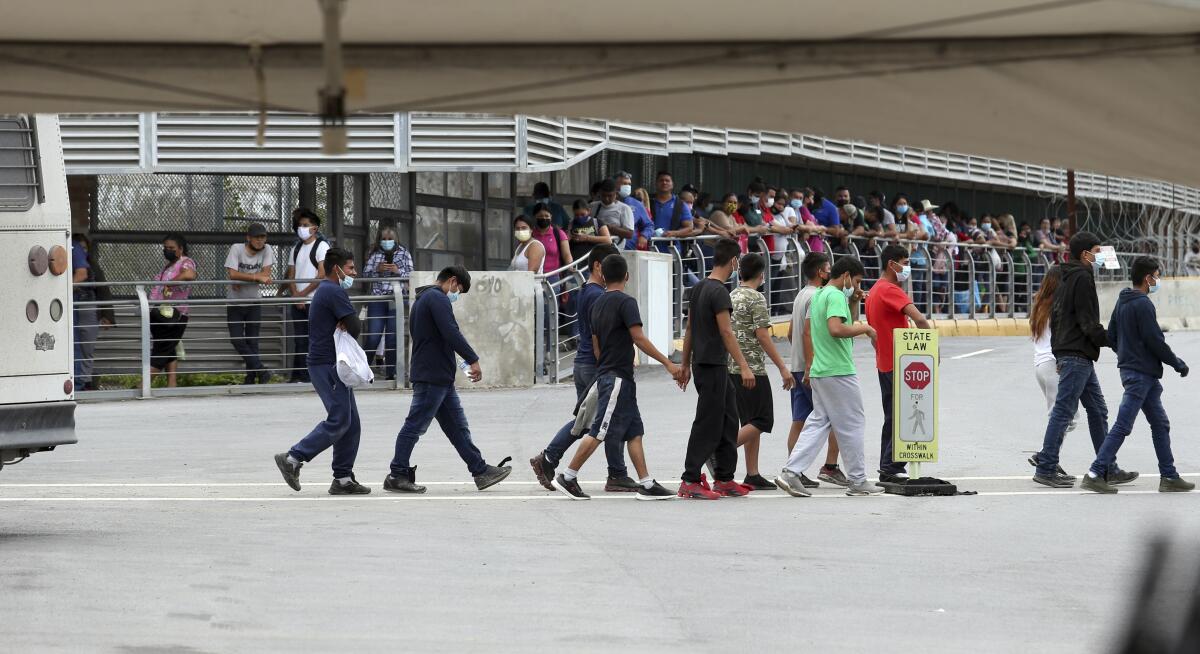 Varios inmigrantes son escoltados hacia un autobús en el Puente Internacional Hidalgo