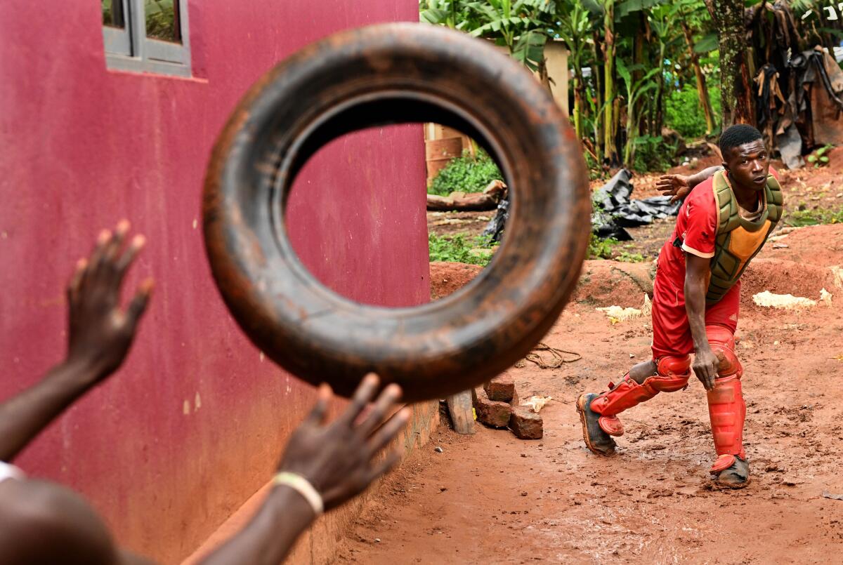 Dennis Kasumba throws an old tire toward the camera