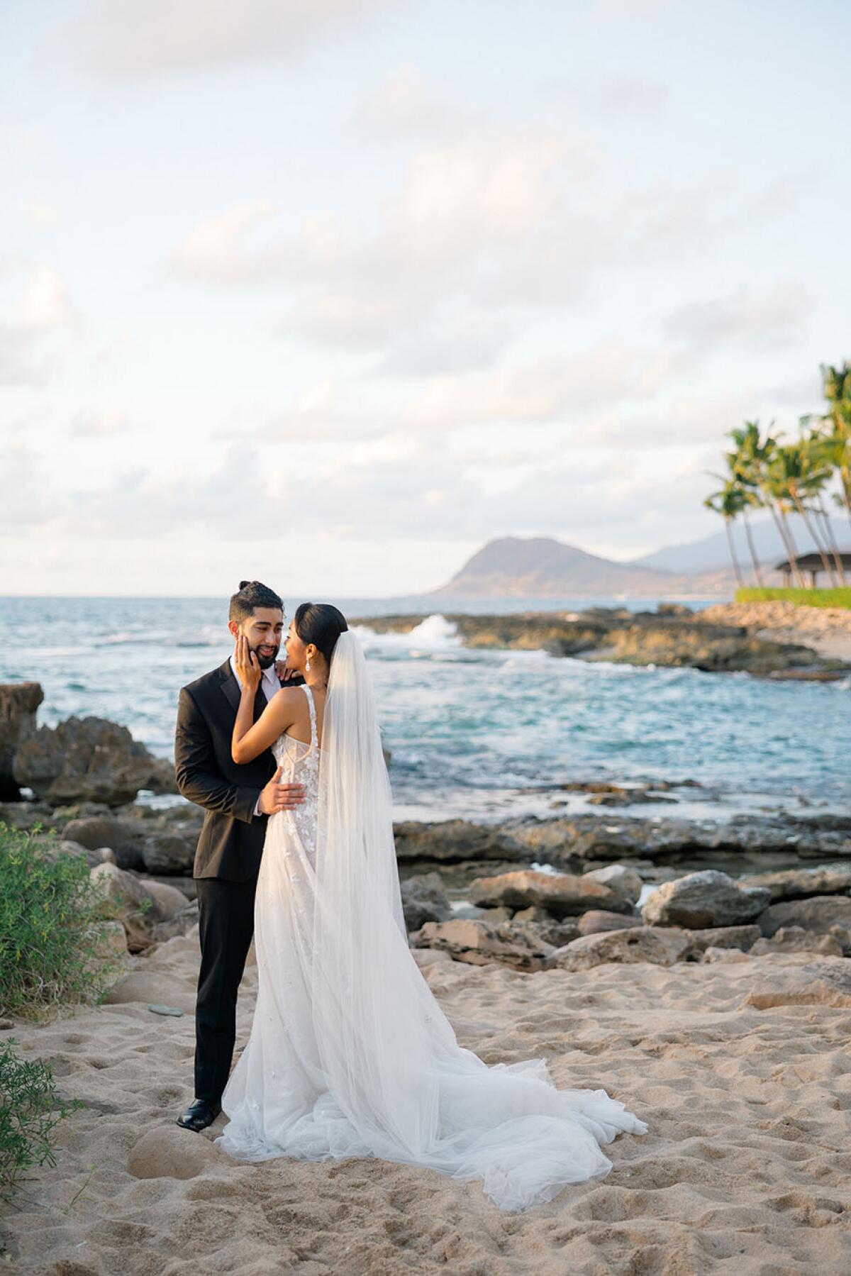 A wedding couple poses on the sands of Four Seasons Oahu.