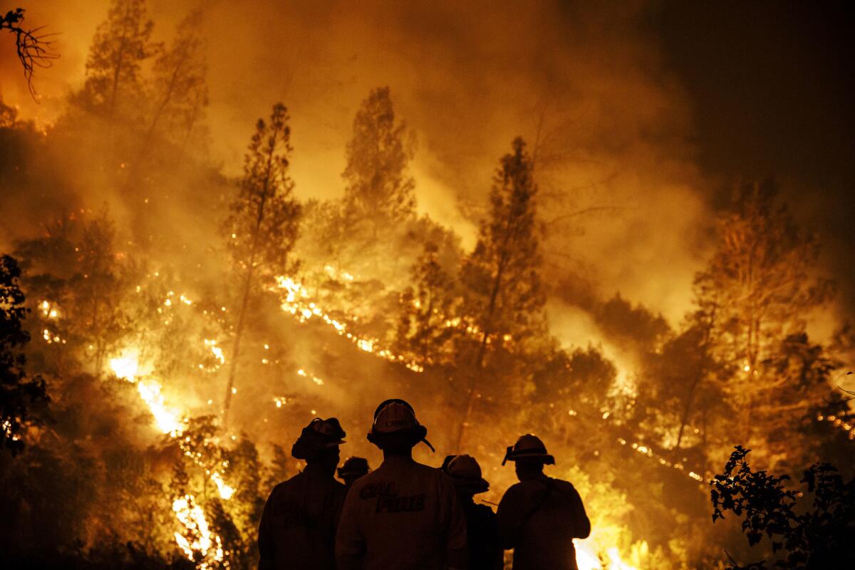 Firefighters monitor a burn operation on top of a ridge near the town of Ladoga, Calif.,