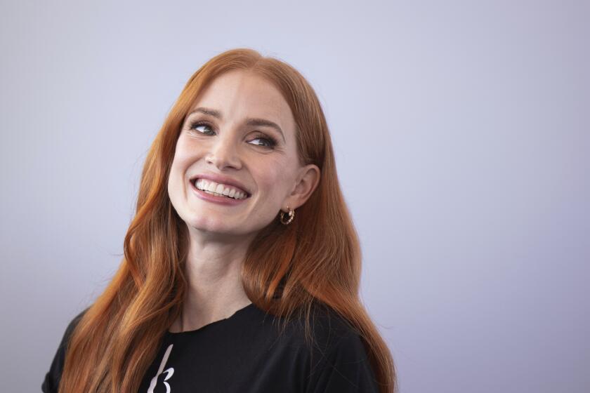Jessica Chastain smiling in a black T-shirt against a white backdrop