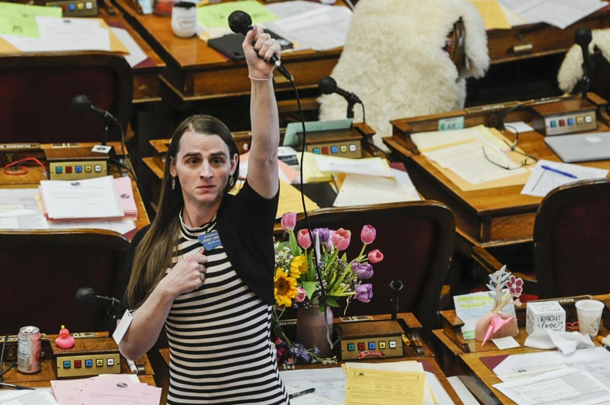Montana state Rep. Zooey Zephyr raises a hand holding a microphone in the House gallery in Helena.
