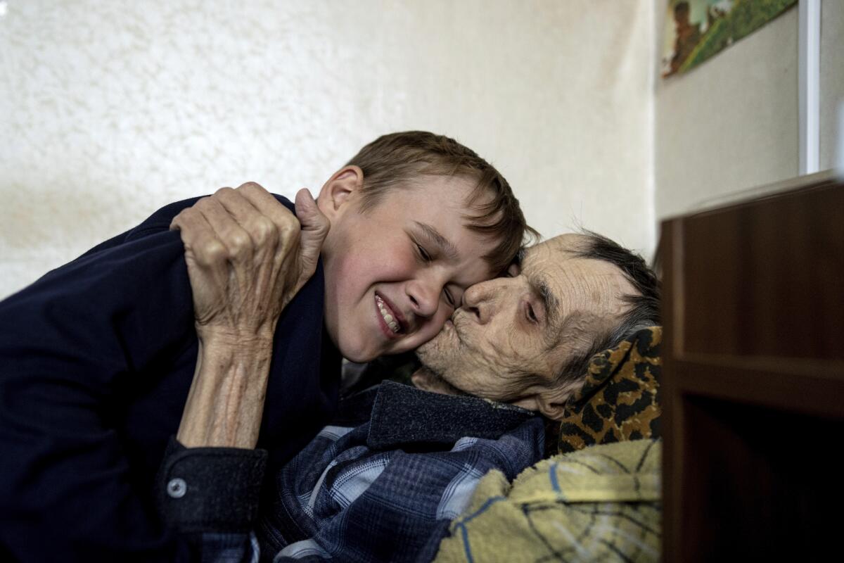 Mykola Svyryd, 70, hugs his son Bohdan, 13, in a shelter for injured and homeless people in Izium, Ukraine, Monday, Sept. 26, 2022. A young Ukrainian boy with disabilities, 13-year-old Bohdan, is now an orphan after his father, Mykola Svyryd, was taken by cancer in the devastated eastern city of Izium. (AP Photo/Evgeniy Maloletka)