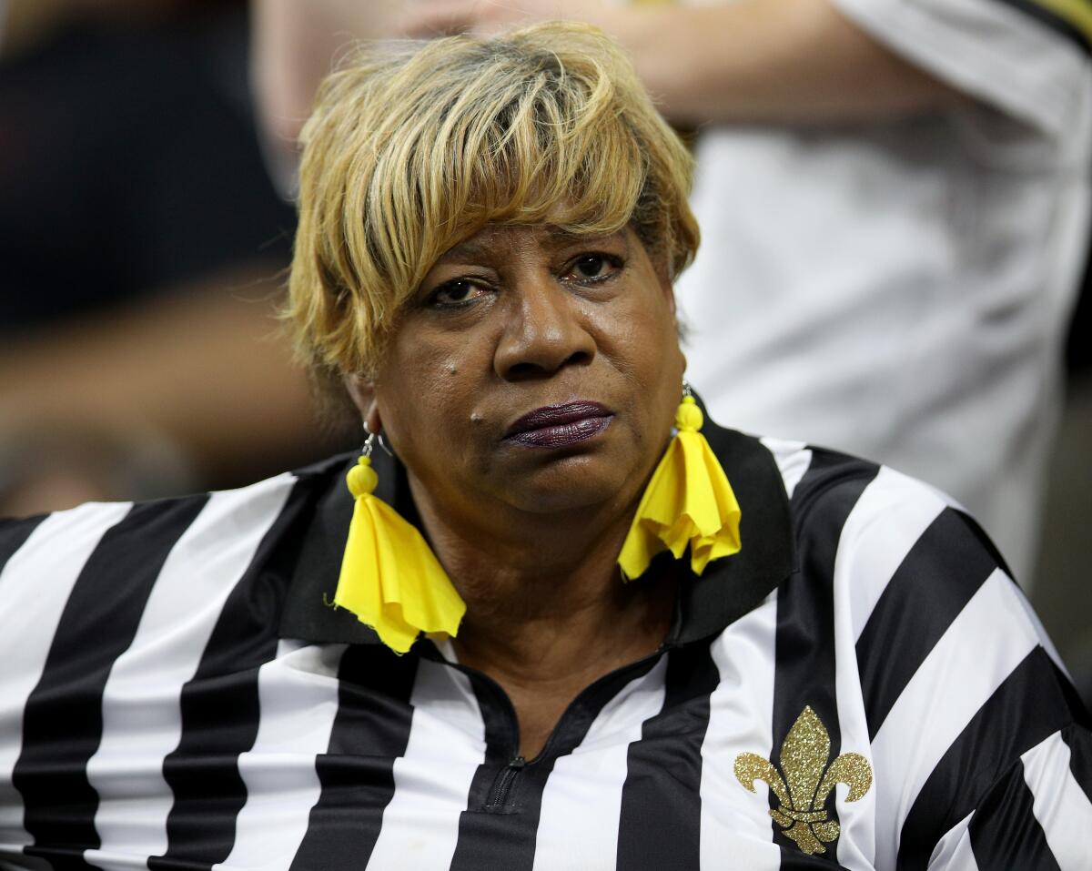 A New Orleans Saints fan in referee attire looks on before a game in 2018.