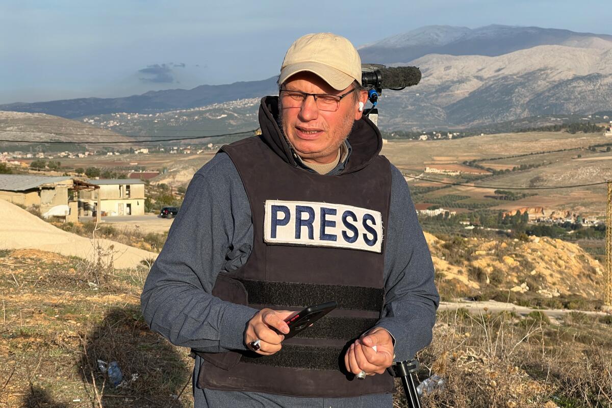 Journalist wearing PRESS vest reporting from conflict zone in southern Lebanon – highlighting dangers faced by media workers covering Israel-Hezbollah tensions