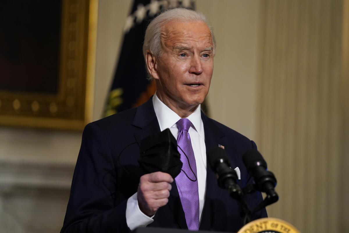 El presidente Joe Biden sostiene su mascarilla 