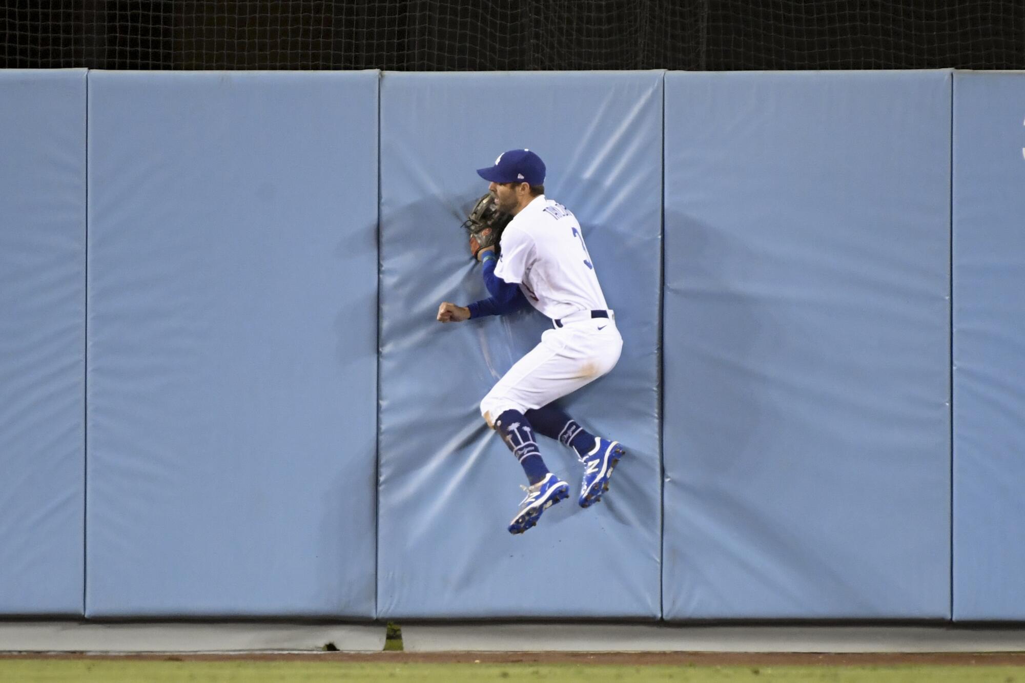  Dodgers center fielder Chris Taylor runs into the outfield wall after catching a ball.
