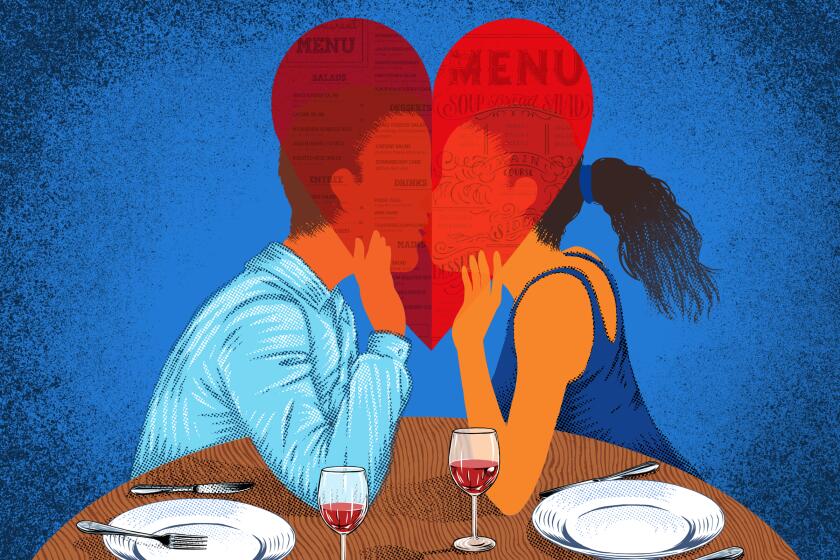 A couple share a kiss behind a menu shaped like a heart.