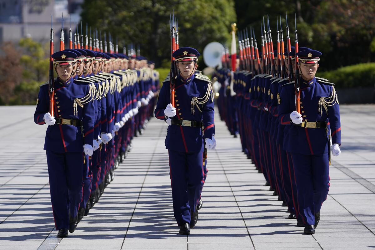 FILE - Japan's honor guard marches into the entrance area of the Ministry of Defense in Tokyo, Friday, Nov. 5, 2021. Japan’s Cabinet on Friday approved a 770 billion yen ($6.8 billion) request for an extra defense budget through March to expedite the purchase of missiles, anti-submarine rockets and other weapons amid rising concern over the escalation of military activities by China, Russia and North Korea. (AP Photo/Hiro Komae, File)