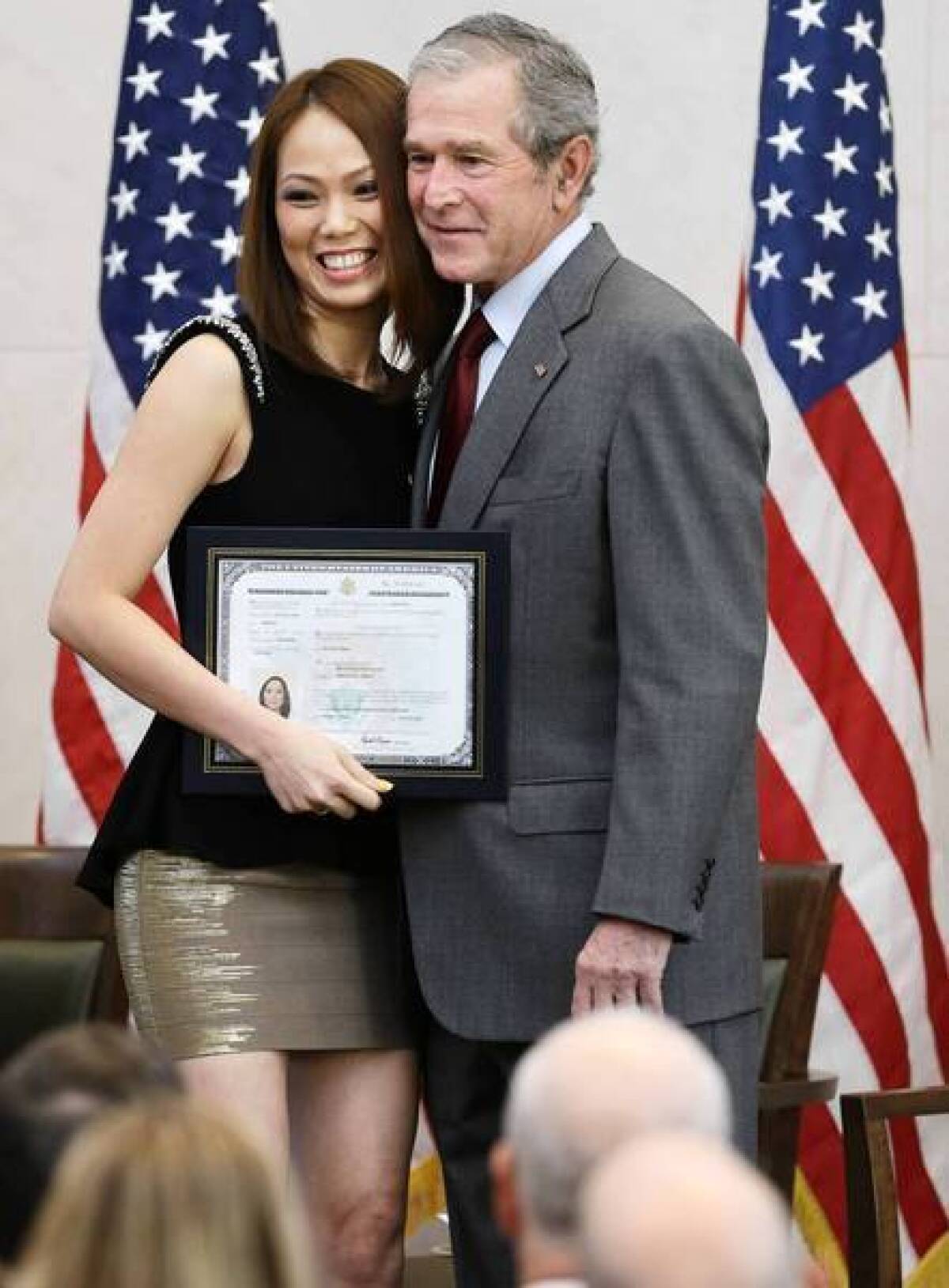 Former President George W. Bush poses with new U.S. citizen Phuong Quynh Ngyuyen during a citizenship ceremony at his presidential library in Dallas. In his comments at the event, Bush called upon Republicans to pass an immigration reform package.