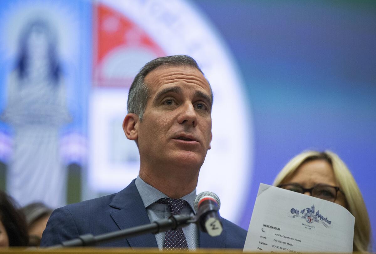 Los Angeles Mayor Eric Garcetti shows a memorandum with COVID-19 city departments guidelines as he takes questions at a news conference in Los Angeles in March.