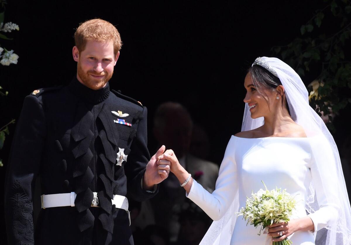The new Duke and Duchess of Sussex hold hands as they exit St. George's Chapel at Windsor Castle after their royal wedding ceremony on Saturday.