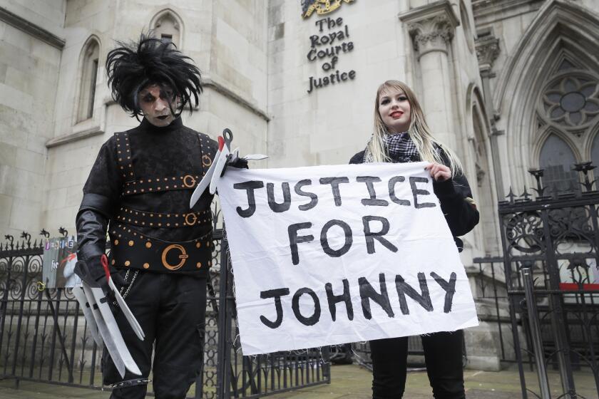 A man dressed as Edward Scissorhands and a woman hold a pro-Johnny Depp sign outside a London court