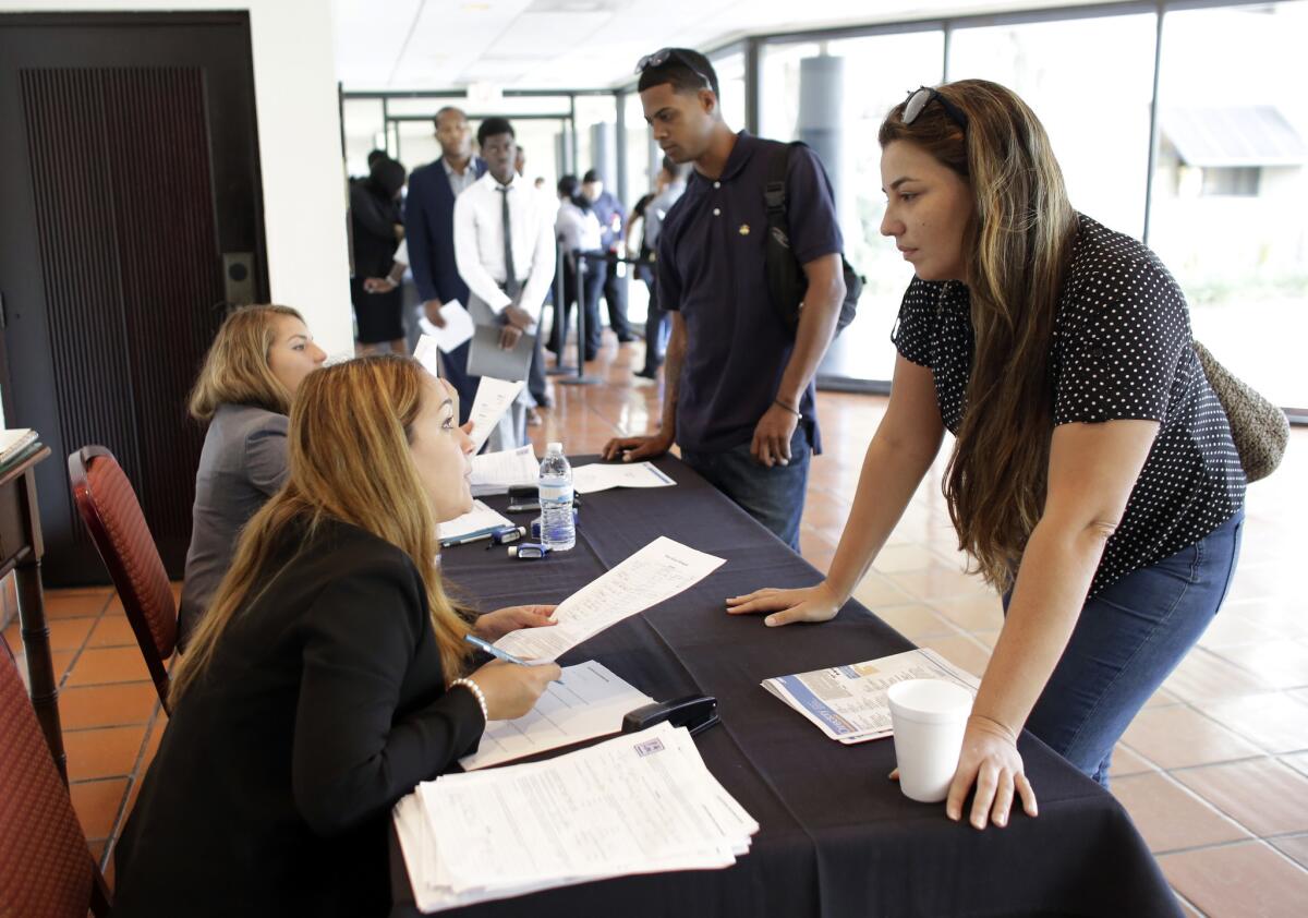 Claudia Caballero, district manager for Aldi, left, talks with job applicant Raisa Rickie at a job fair in Miami Lakes, Fla., on July 19.