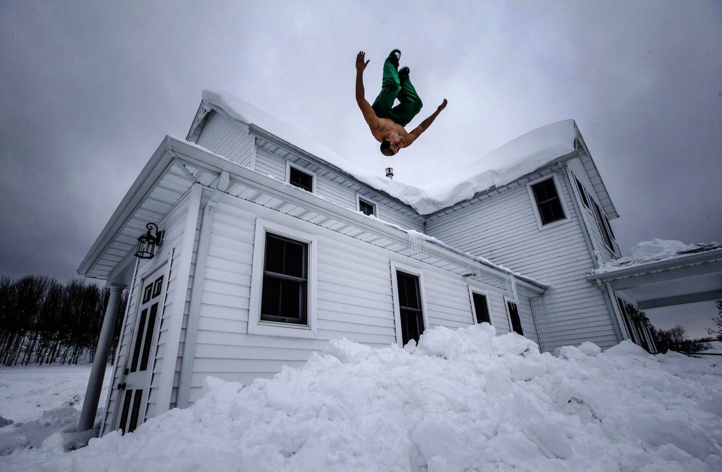 Phil Mohun does a back flip off of his family home after clearing snow from the roof following a massive snowstorm in Cowlesville, New York, November 22, 2014.