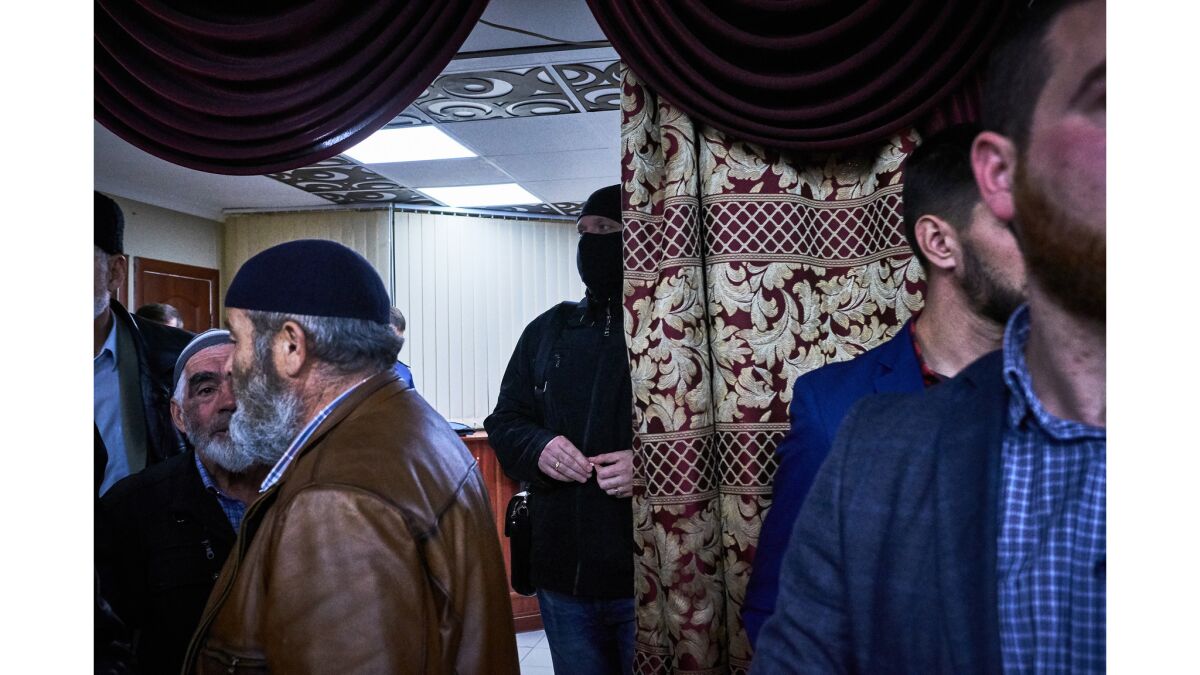 A masked member of Russia's Office of Counter-Terrorism stands in the entrance of a banquet hall where the Crimean Solidarity civil society group holds its monthly meeting in Simferopol.