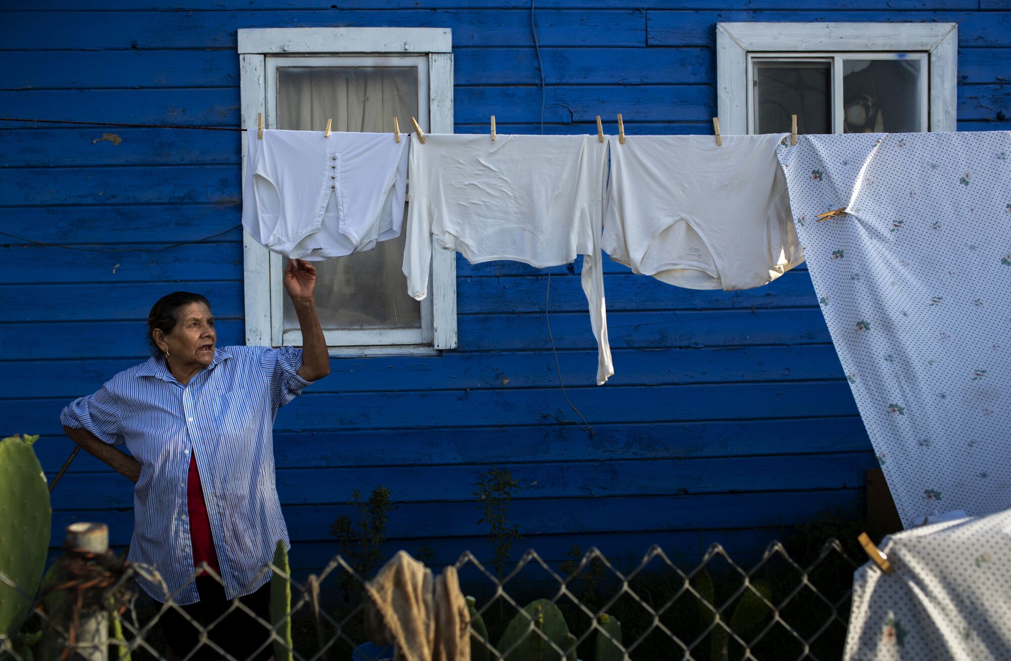 Estella Lopez waits as clothes dry on a line at her home in Stratford.