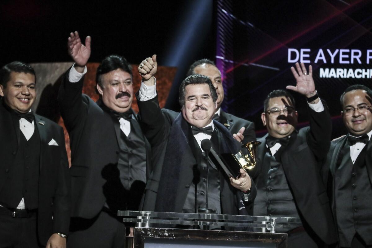 six men in tuxes onstage wave to the crowd as they accept an award