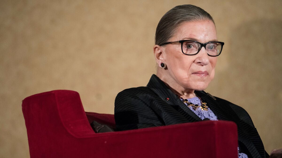 Supreme Court Justice Ruth Bader Ginsburg sits in a red chair