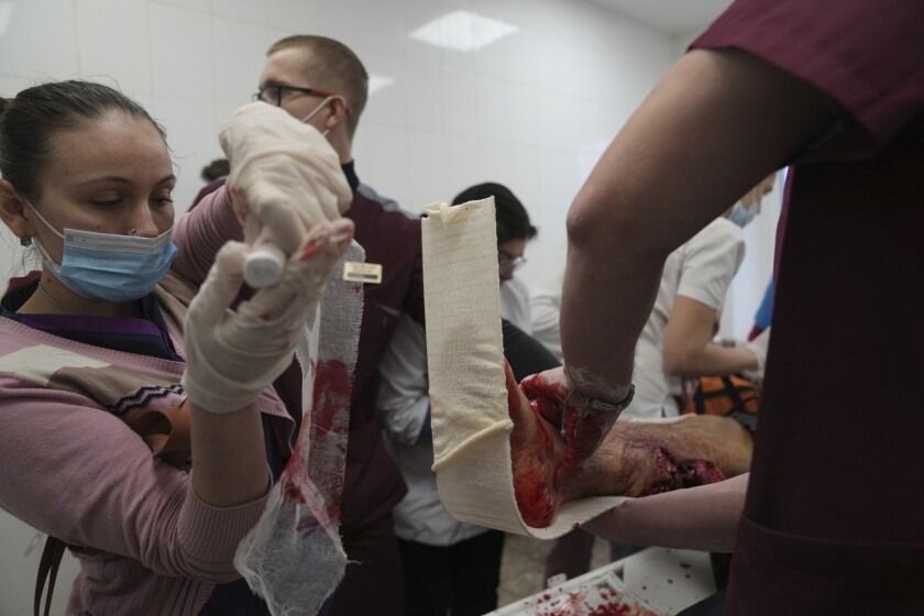 Medical workers and volunteers bandage a bleeding foot and leg