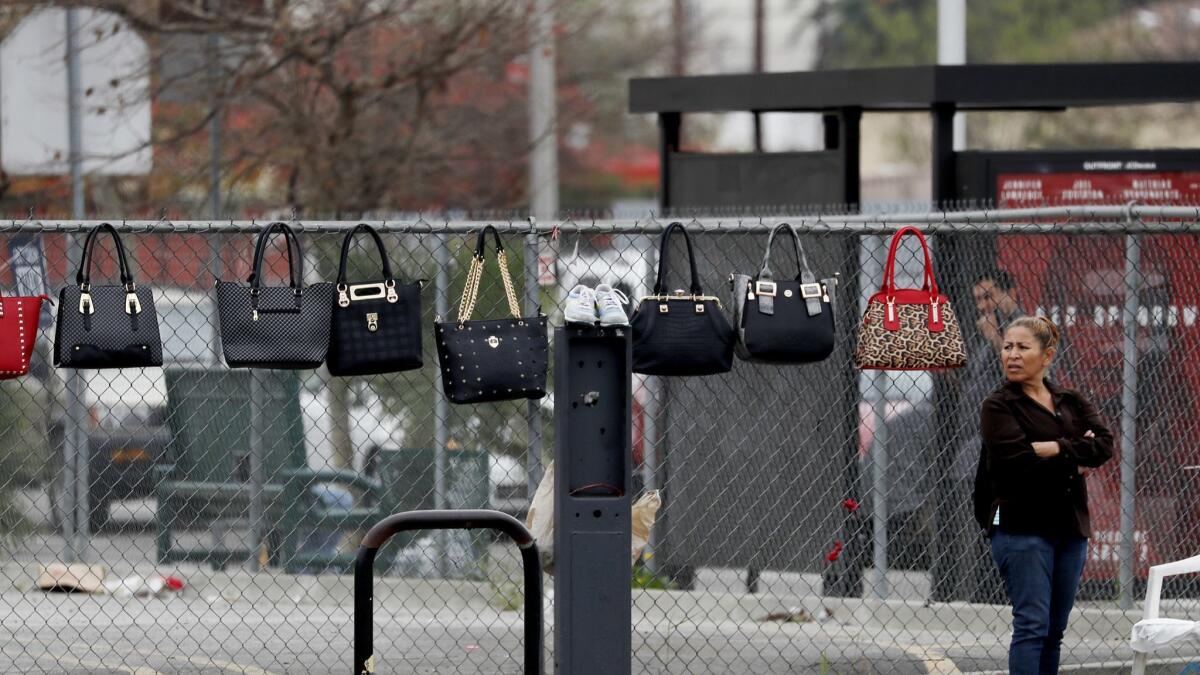 Handbags for sale hang on a fence surrounding a vacant lot at the corner of Manchester and Vermont avenues in South Los Angeles.