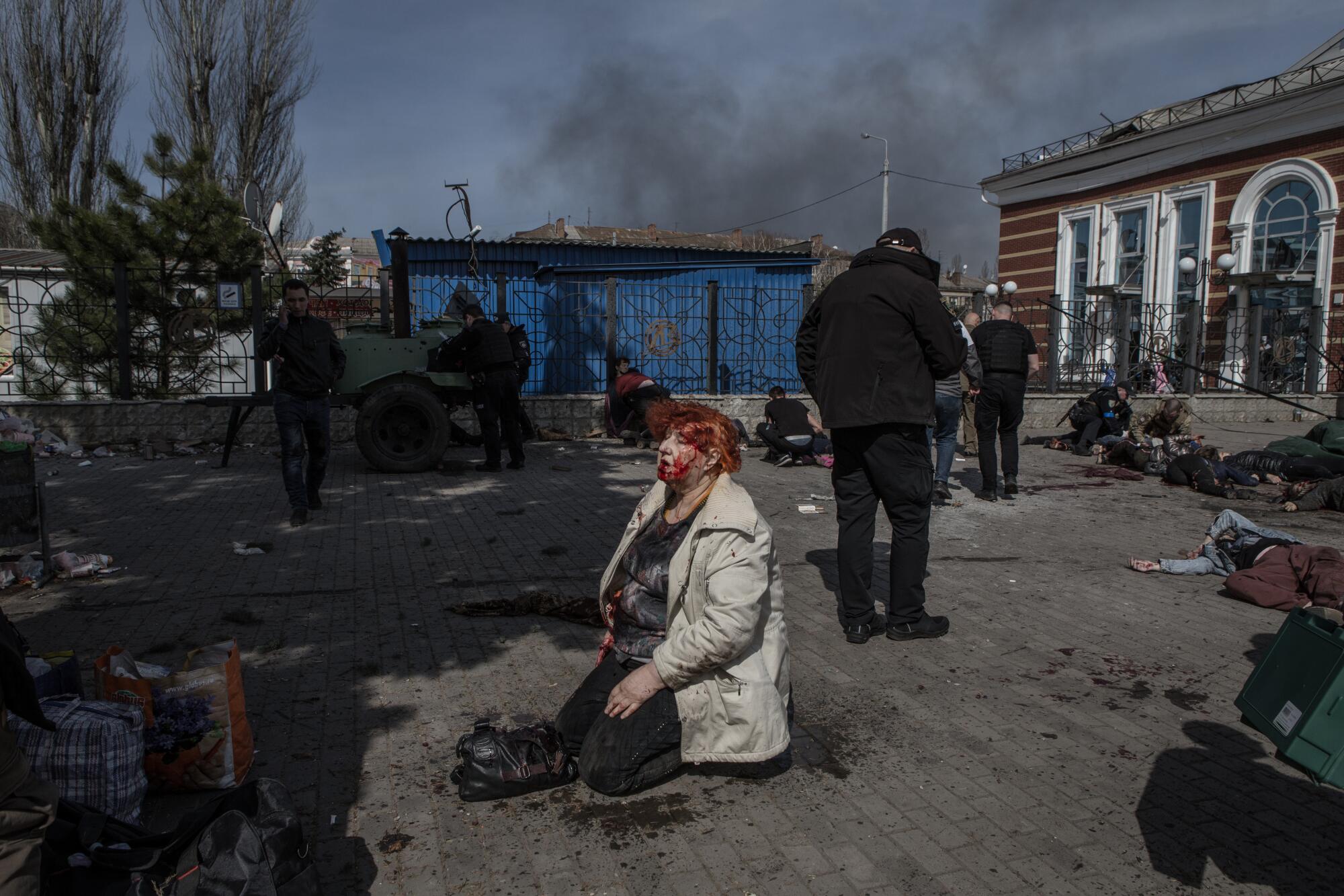 An injured person kneels on the ground after the attack on a Ukrainian train station.