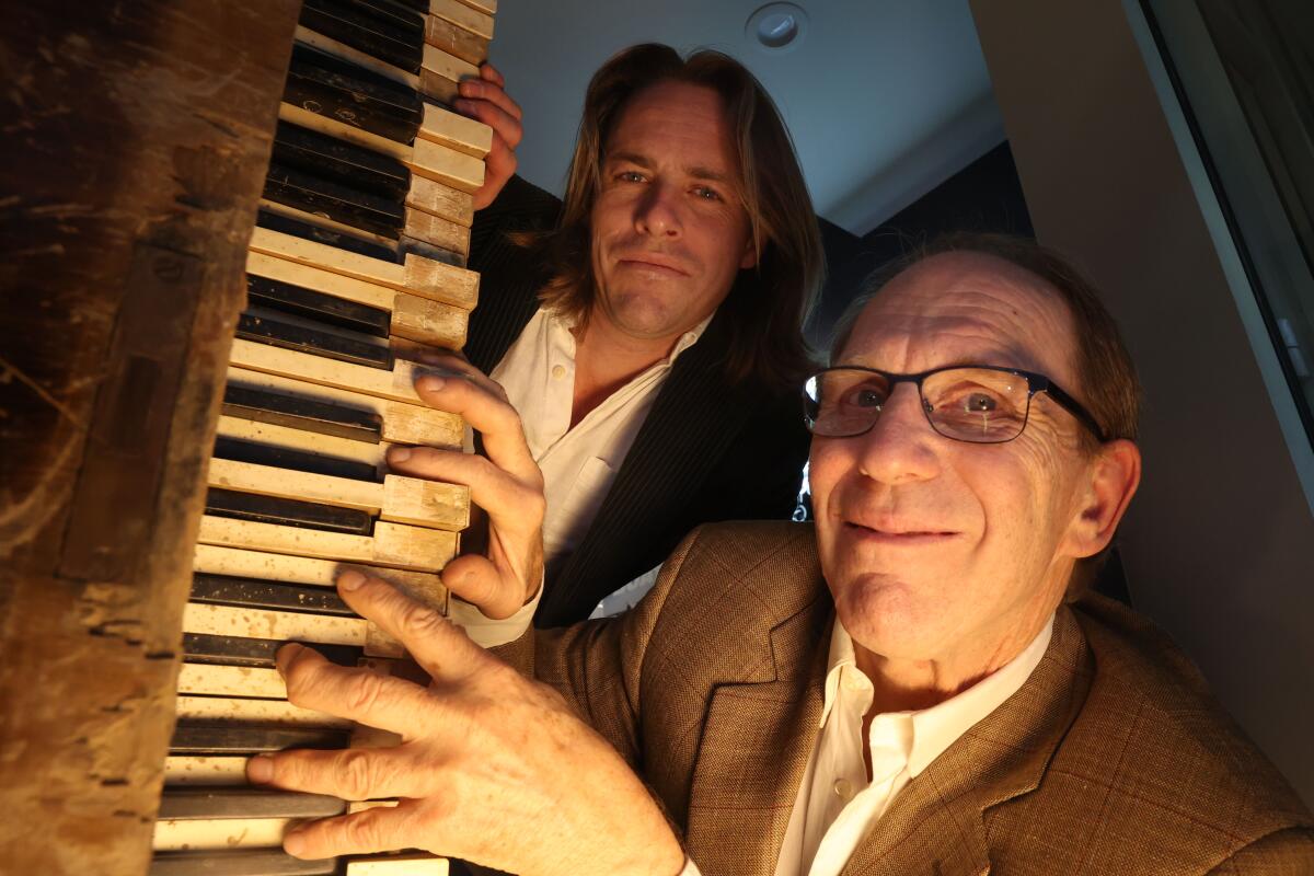 Kyril Kasimoff, right, and Dirk Braun pose for a portrait with a 149-year-old piano.