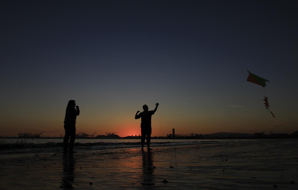 Fabi Sandoval and Erick Gasca try to launch their kite on a windless evening on the shoreline of Long Beach.