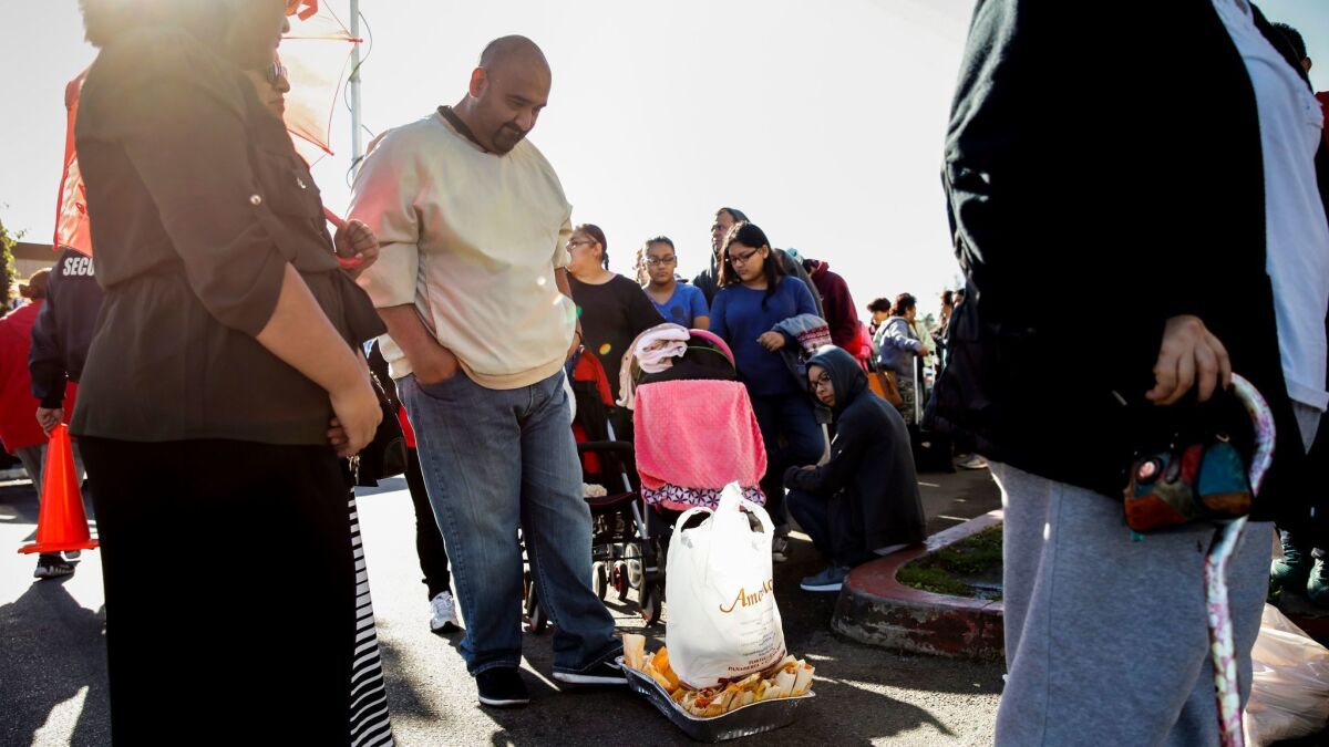 John Cárdenas empuja en el suelo una fuente de tamales en mal estado y una bolsa de masa, mientras espera en fila en Amapola Deli and Market, en Downey, por su reembolso (Jay L. Clendenin / Los Angeles Times).