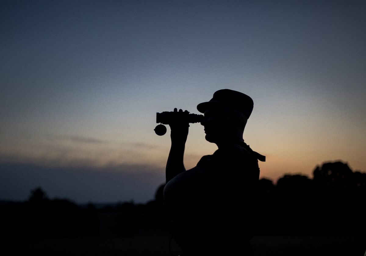 FILE - In this Friday, July 9, 2021 file photo, a member of the Lithuania State Border Guard Service looks through binoculars as he patrols on the border with Belarus, near the village of Purvenai, Lithuania. Lithuania has ordered its border guards to turn away, by force if needed, migrants attempting to enter the Baltic country as the rapidly growing number of immigrants illegally crossing from neighboring Belarus has emerged a major foreign policy issue to the small European Union nation. (AP Photo/Mindaugas Kulbis, File)
