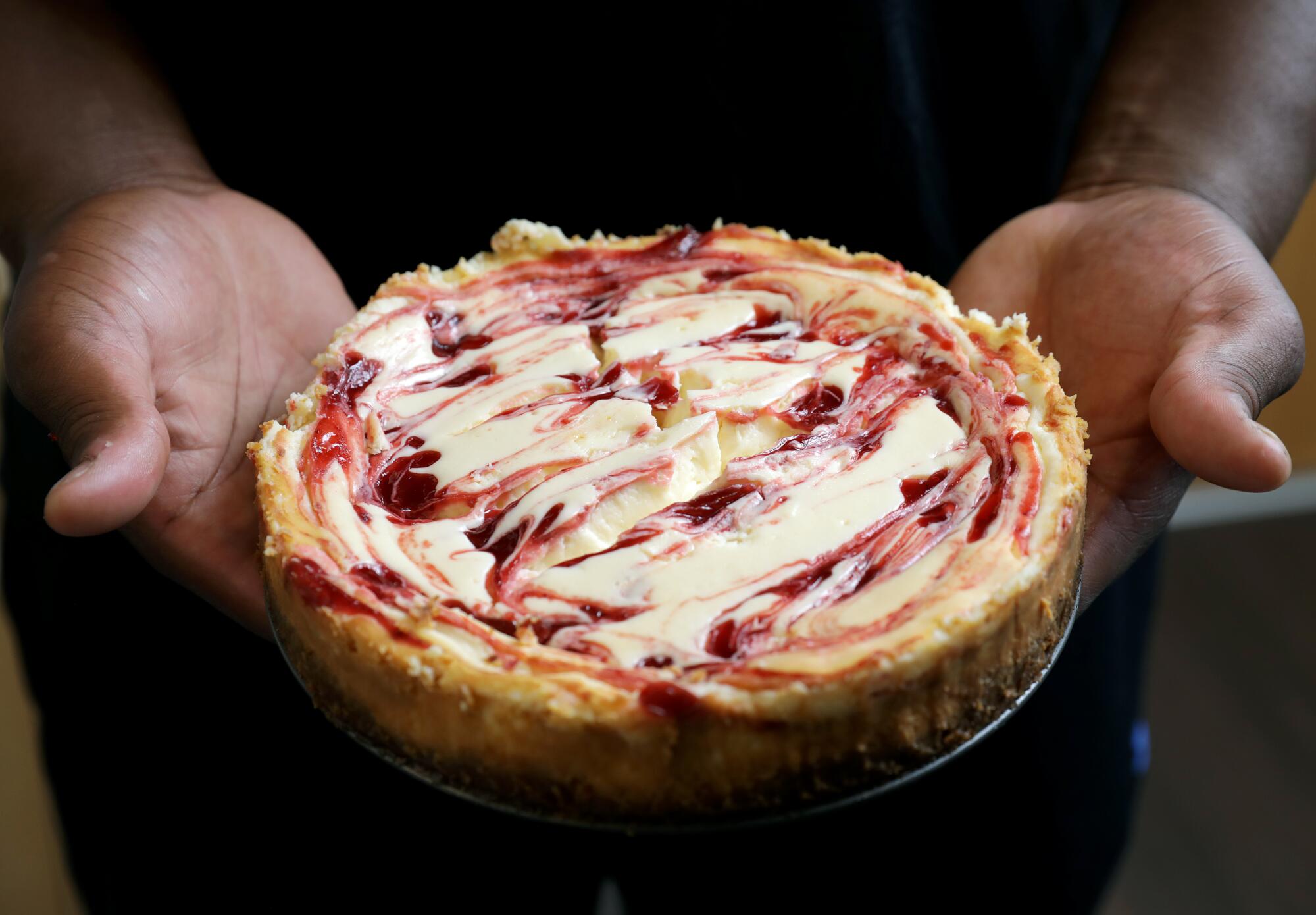 The finished product: UCLA defensive lineman Otito Ogbonnia holds up a strawberry cheesecake he made in his apartment 