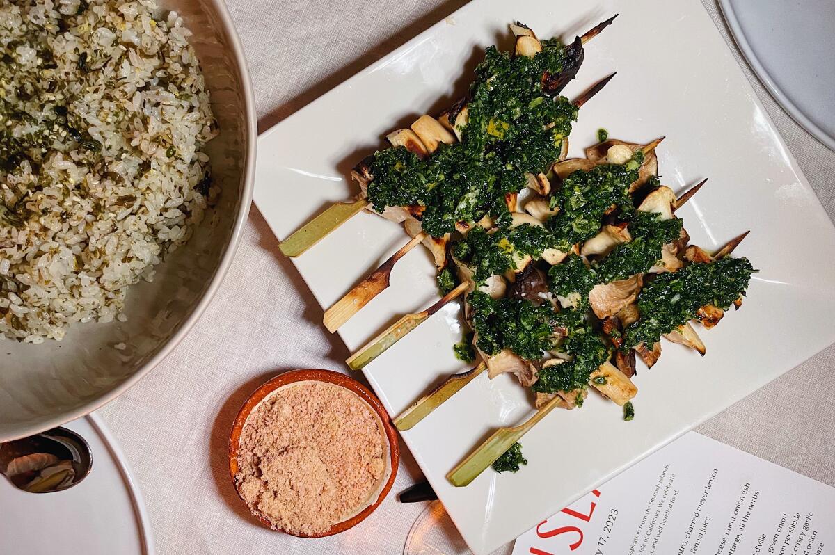 An overhead photo of mushroom skewers on a table with a bowl of nori rice