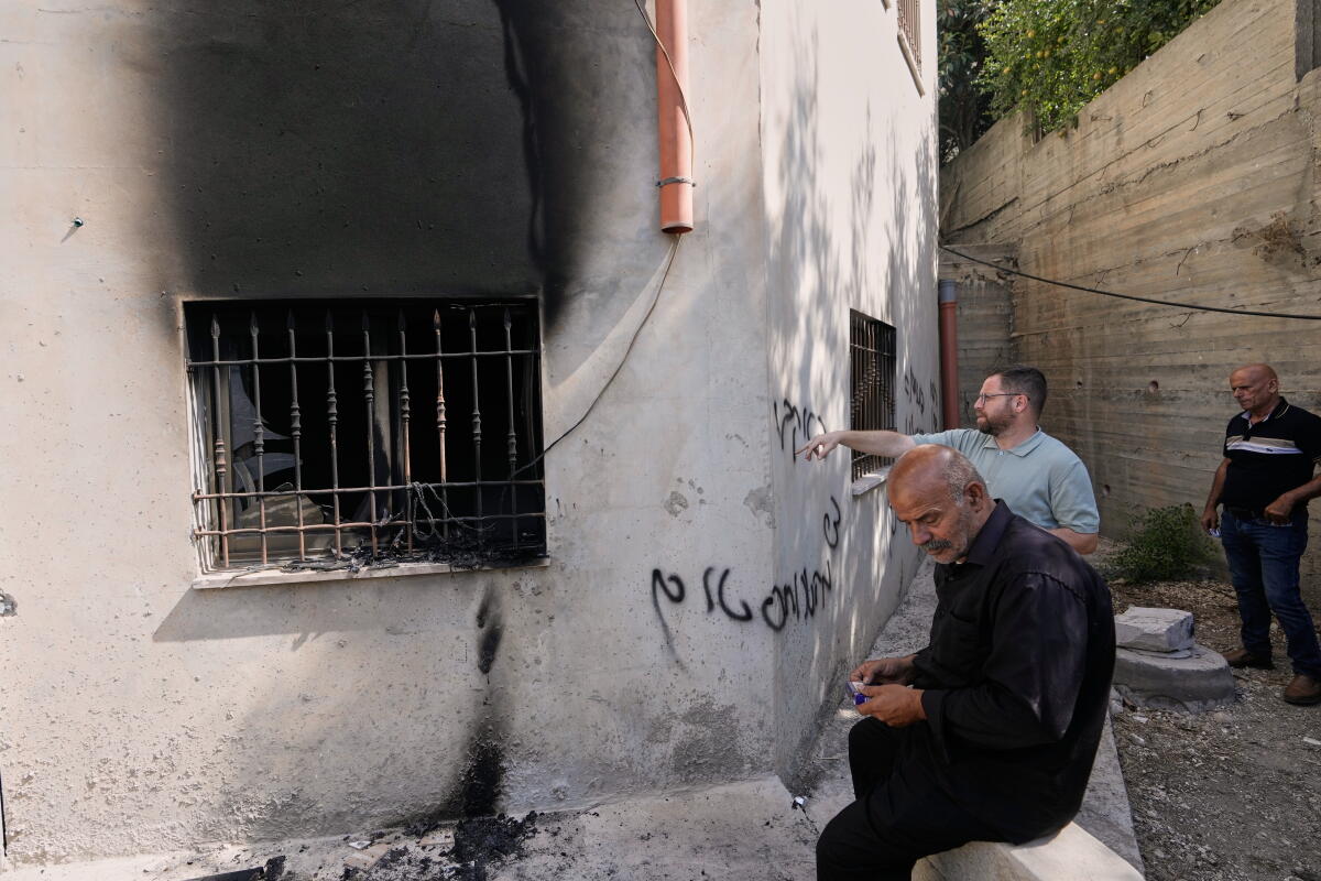 Men examine graffiti and damage on the exterior of a mosque