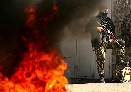 A Palestinian militant takes position during fighting with Israeli troops in the Zeitun neighborhood of Gaza City. At least 19 Palestinians and an Ecuadorean kibbutz volunteer were killed in the fighting, which occurred amid peace talks between Israel and Palestinian President Mahmoud Abbas.