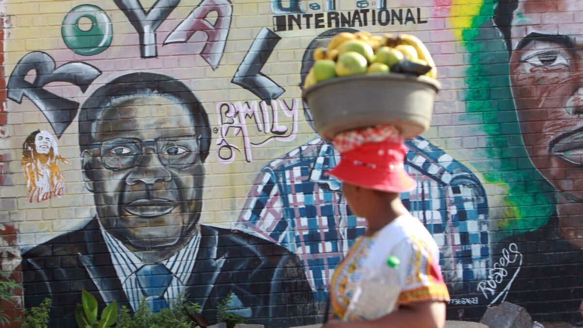 A Zimbabwean woman walks past a mural of President Robert Mugabe in Harare, the capital, in 2017
