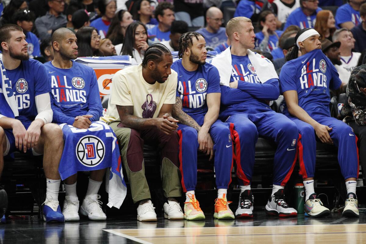 Clippers star Kawhi Leonard, in white T-shirt, sits with teammates on the bench during Game 3 of the series vs. the Suns.