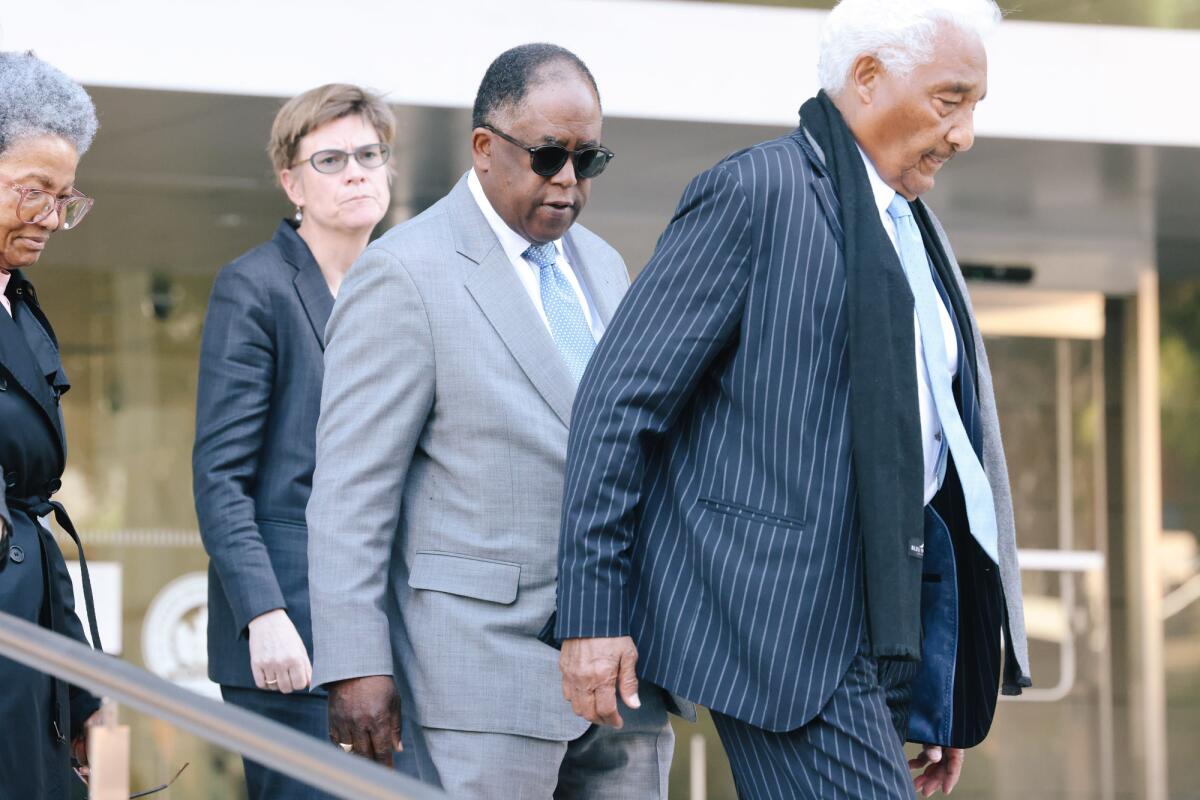 Four people in formal attire leaving a courthouse