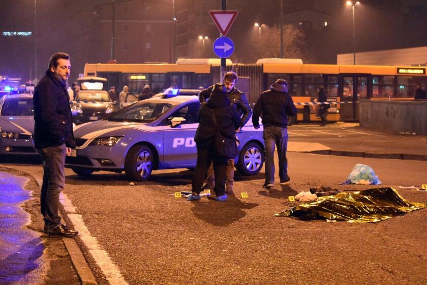 Italian police stand around the body of suspect Anis Amri after a shootout in Milan's Sesto San Giovanni neighborhood early Friday.