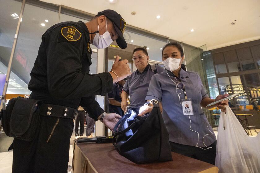Guardas de seguridad revisan el bolso de un visitante en un acceso al centro comercial Siam Paragon en Bangkok, Tailandia, el 4 de octubre de 2023, un día después de que un adolescente abrió fuego en el interior del recinto y mató a dos personas. (AP Foto/Wason Wanichakorn)