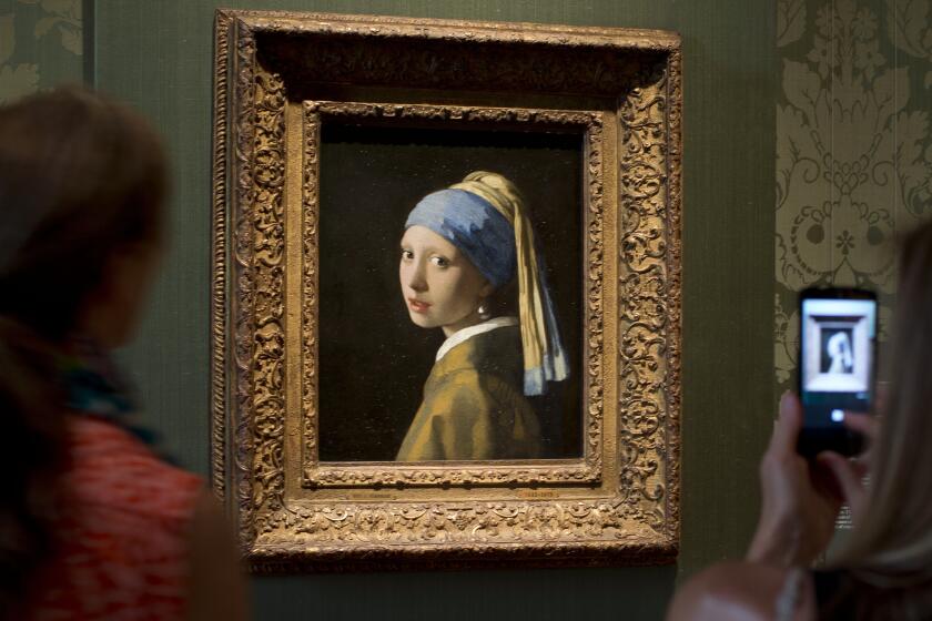 FILE- Visitors take pictures of Johannes Vermeer's Girl with a Pearl Earring (approx. 1665) during a preview for the press of the renovated Mauritshuis in The Hague, Netherlands, June 20, 2014. The Vermeer masterpiece “Girl with a Pearl Earring” has become the latest artwork targetted by climate activists in a protest at the Mauritshuis museum in The Hague on Thursday, Oct. 27, 2022. The museum did not immediately return calls and emails for comment after a video of the protest was posted on Twitter. (AP Photo/Peter Dejong, file)
