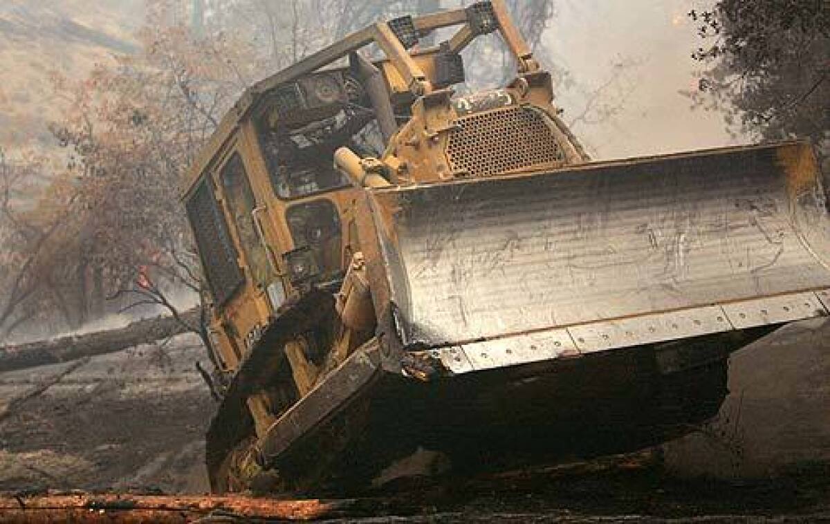 Bulldozer operator Chris Ivey makes his way over a log near Arrowbear in an attempt to keep fire from jumping California 18.