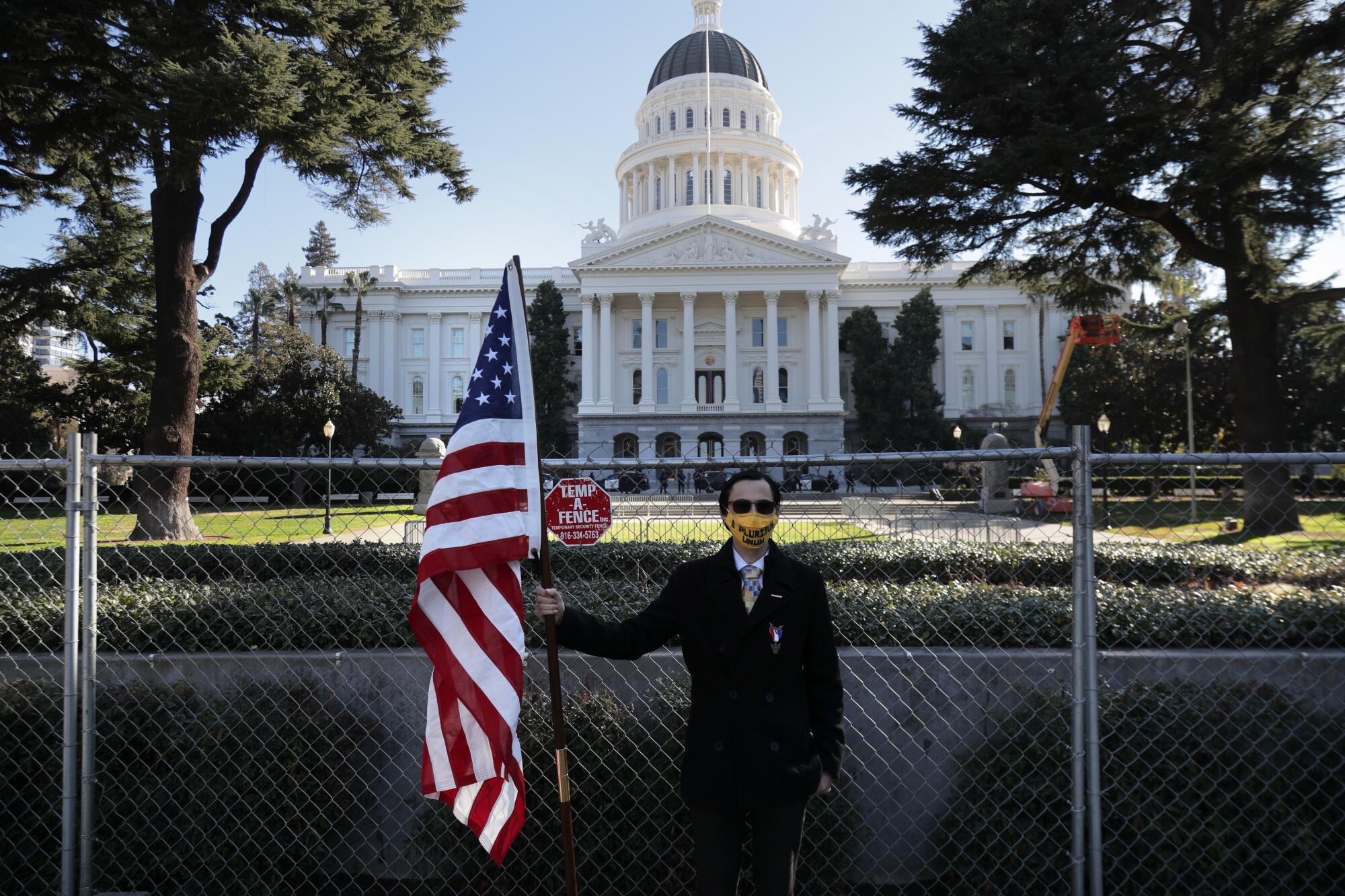 Christian Alvarado stands with an American flag in solidarity with police and legislators near the Capitol in Sacramento.