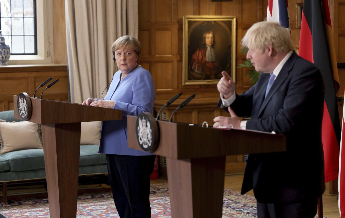 Angela Merkel and Boris Johnson stand at lecterns in front of their countries' flags.