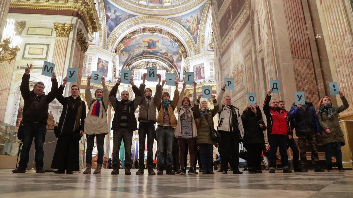 Russians protesting the transfer of St. Isaac's Cathedral to the Russian Orthodox Church hold cards reading, "The museum to the city!" in the cathedral in St. Petersburg.